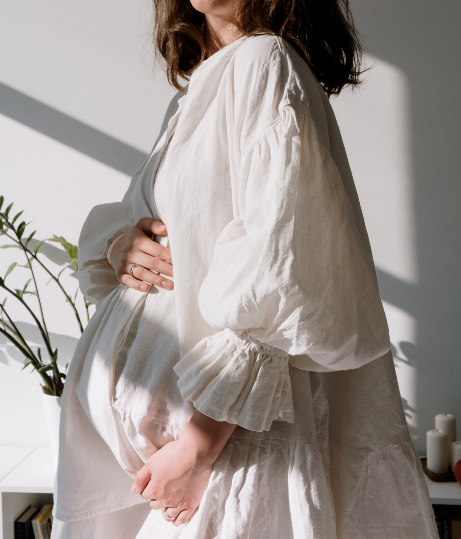 expectant mother in cream knitwear gently cradling her baby bump